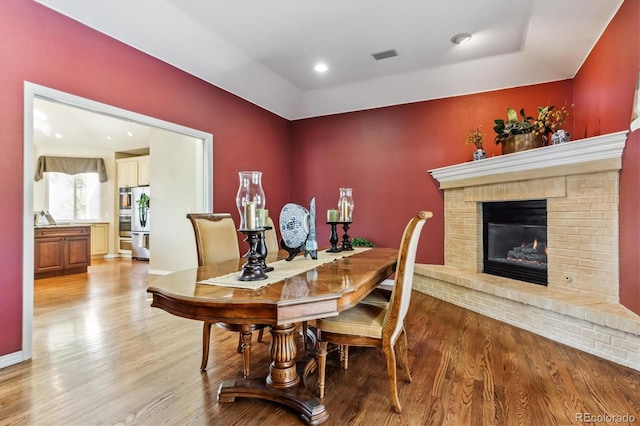 dining area with visible vents, baseboards, recessed lighting, light wood-style floors, and a brick fireplace