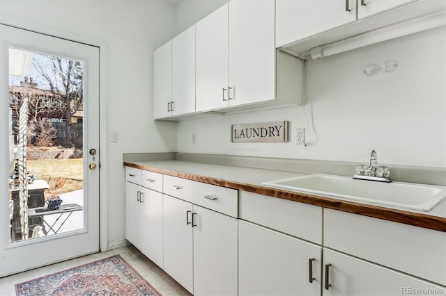 kitchen featuring white cabinetry, light countertops, and a sink