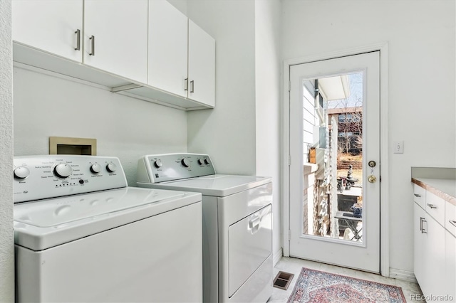 clothes washing area with visible vents, cabinet space, and separate washer and dryer