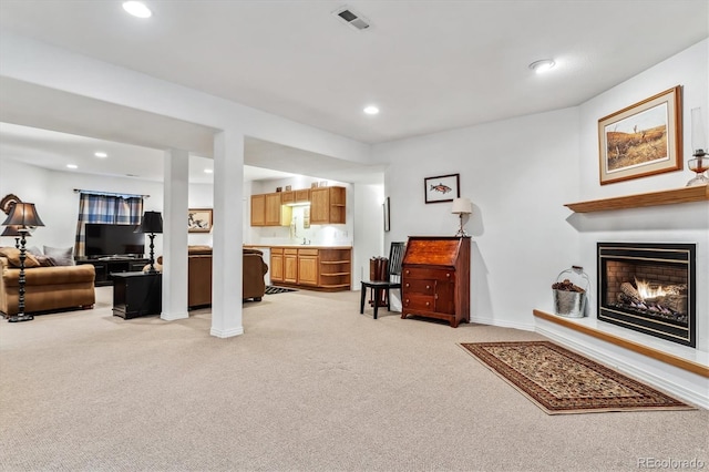 living room featuring recessed lighting, visible vents, light colored carpet, and a lit fireplace