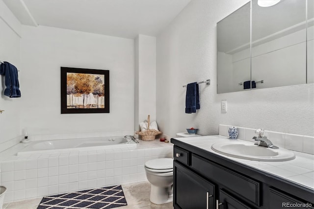 full bathroom featuring toilet, vanity, a garden tub, and a textured wall