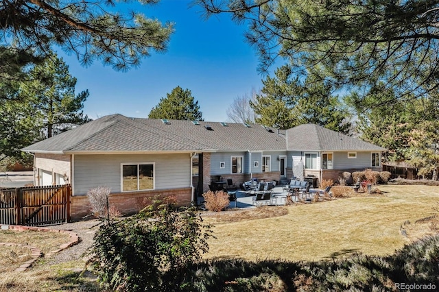 back of property with fence, an attached garage, a lawn, a patio area, and brick siding