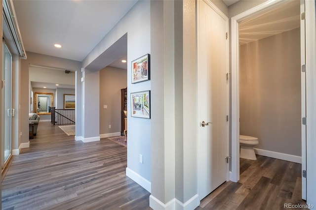 hallway featuring recessed lighting, baseboards, dark wood-style flooring, and an upstairs landing