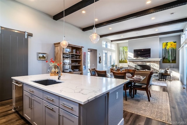 kitchen featuring a barn door, a center island with sink, gray cabinetry, sink, and decorative light fixtures