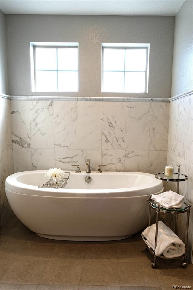 bathroom with tile walls, tile patterned flooring, and a bath