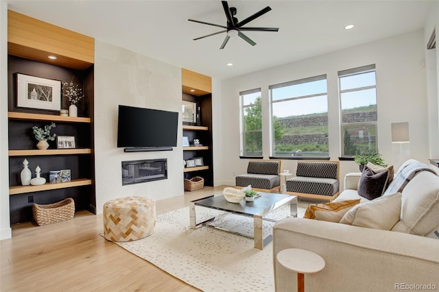 3436 W 154th Ave, Broomfield, CO 80023 - living room with wood finished floors, ceiling fan, a tiled fireplace, built in features, and recessed lighting
