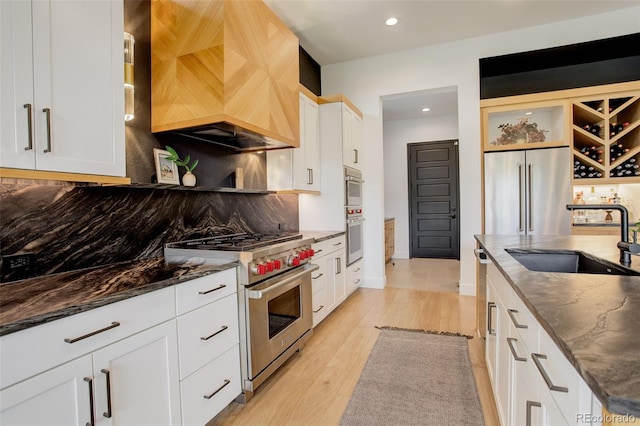 3436 W 154th Ave, Broomfield, CO 80023 - kitchen featuring premium appliances, custom exhaust hood, backsplash, dark stone counters, and recessed lighting