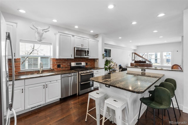 449 S Humboldt St, Denver, CO 80209 - kitchen featuring appliances with stainless steel finishes, a breakfast bar area, a sink, dark wood-style flooring, and recessed lighting