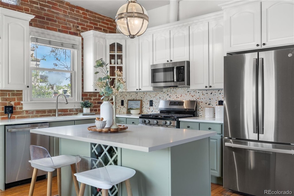 624 E 18th Ave Unit 3, Denver, CO 80203 - kitchen featuring stainless steel appliances, a kitchen bar, light countertops, and brick wall