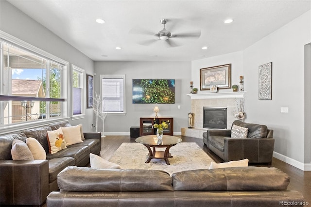 living room with ceiling fan, a premium fireplace, and dark hardwood / wood-style flooring