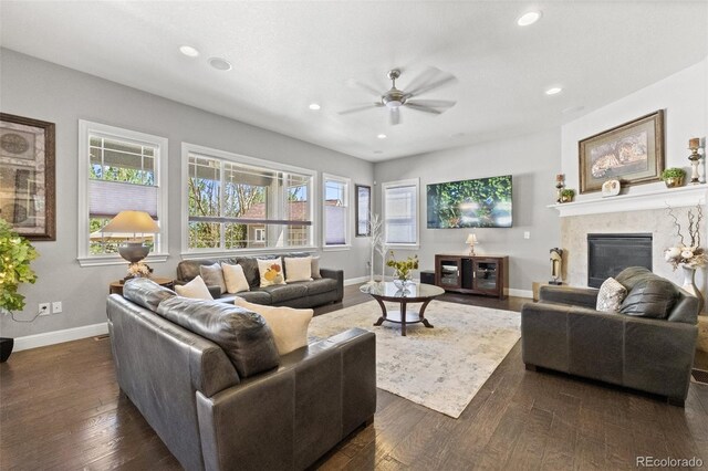 living room featuring ceiling fan, a premium fireplace, plenty of natural light, and dark hardwood / wood-style floors