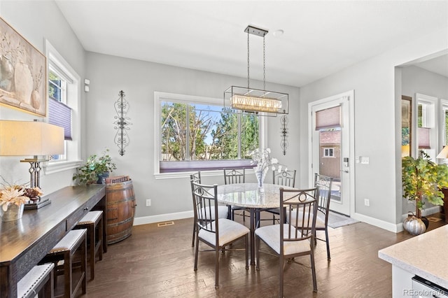 dining space with a chandelier, plenty of natural light, and dark hardwood / wood-style flooring