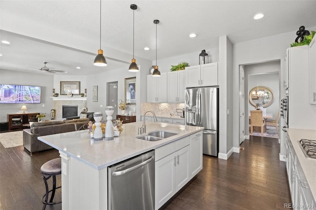 kitchen with dark hardwood / wood-style floors, a center island with sink, sink, white cabinets, and appliances with stainless steel finishes