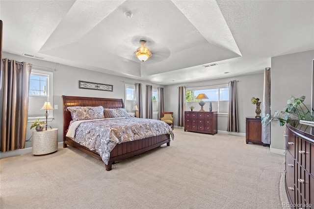 carpeted bedroom featuring multiple windows, a tray ceiling, and ceiling fan