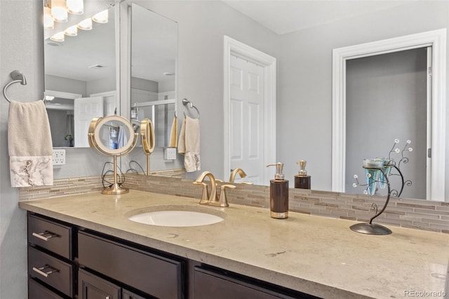 bathroom featuring vanity, decorative backsplash, and walk in shower