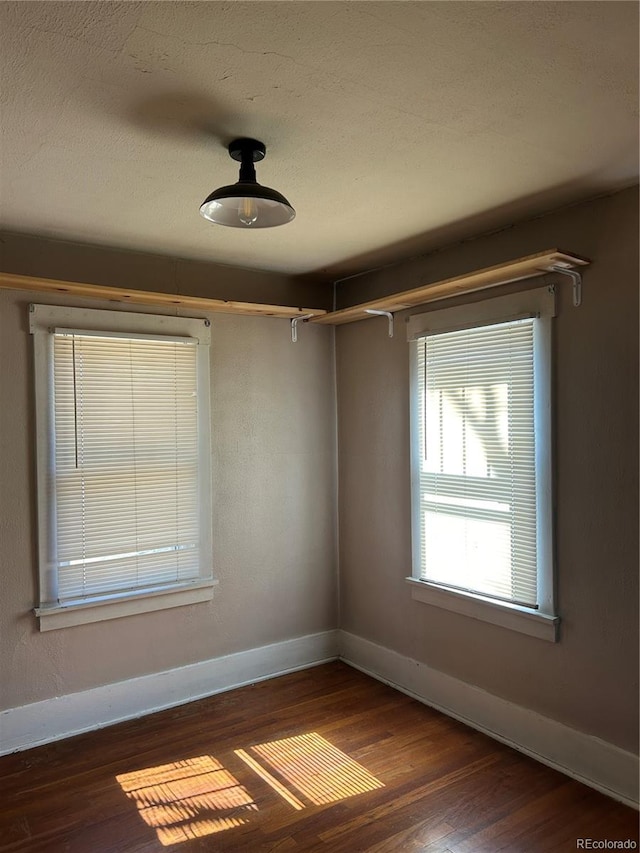 unfurnished room featuring baseboards, a textured ceiling, and wood finished floors