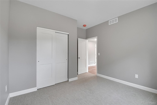 unfurnished bedroom with a closet, visible vents, carpet, and baseboards