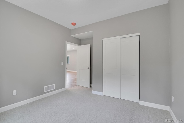 unfurnished bedroom with visible vents, baseboards, a closet, and carpet flooring