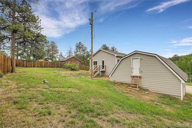 exterior space featuring a gambrel roof, a lawn, roof with shingles, and fence