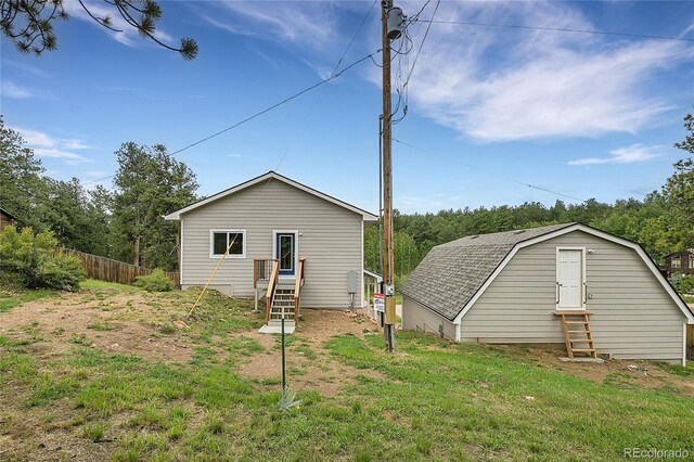 rear view of property featuring fence, a gambrel roof, and roof with shingles