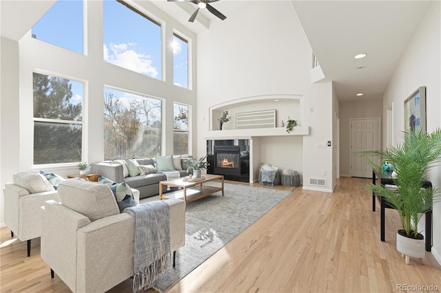 living room featuring ceiling fan, light hardwood / wood-style floors, and a high ceiling