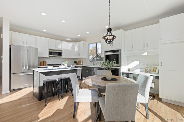 kitchen featuring decorative light fixtures, light wood-type flooring, white cabinetry, and stainless steel appliances