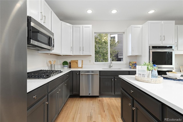 kitchen with white cabinetry, sink, light wood-type flooring, and stainless steel appliances