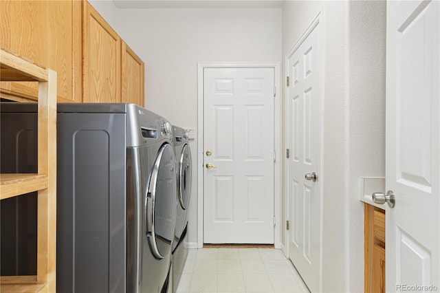 laundry room featuring washer and clothes dryer, light tile patterned flooring, and cabinets