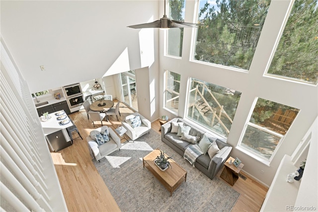 living room featuring a towering ceiling, hardwood / wood-style flooring, and ceiling fan