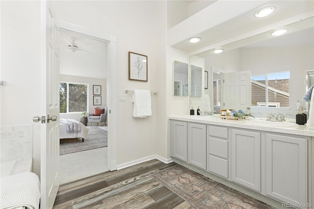 bathroom featuring hardwood / wood-style flooring, vanity, ceiling fan, and vaulted ceiling