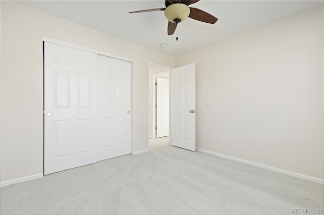 unfurnished bedroom with ceiling fan, light carpet, and a closet