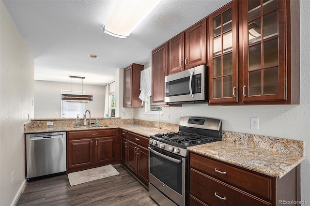 22002 E Irish Dr, Aurora, CO 80016 - kitchen featuring appliances with stainless steel finishes, dark wood finished floors, glass insert cabinets, light stone countertops, and decorative light fixtures