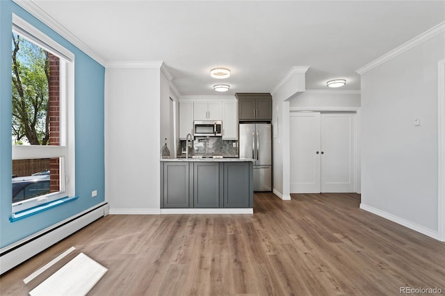 320 S Ames St Unit 5, Lakewood, CO 80226 - kitchen with stainless steel appliances, baseboard heating, tasteful backsplash, wood finished floors, and light countertops