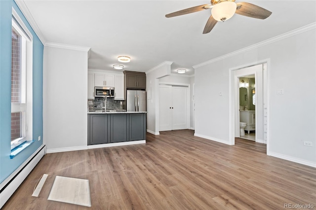 320 S Ames St Unit 5, Lakewood, CO 80226 - kitchen with stainless steel appliances, baseboard heating, light countertops, backsplash, and light wood-style flooring