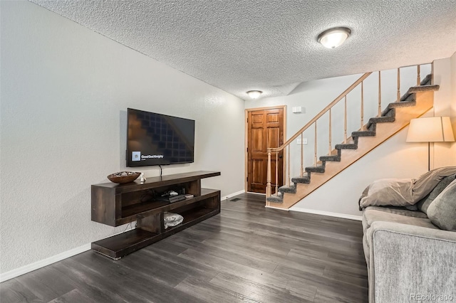 living room with stairway, wood finished floors, baseboards, and a textured ceiling