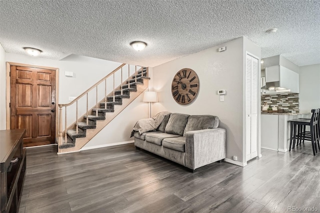 living area with stairs, wood finished floors, baseboards, and a textured ceiling