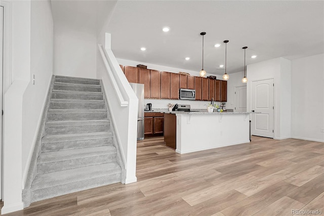 kitchen with a breakfast bar area, a center island with sink, recessed lighting, light wood-type flooring, and stainless steel appliances
