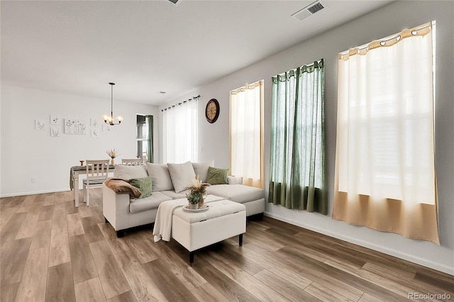living room featuring baseboards, visible vents, wood finished floors, and a chandelier