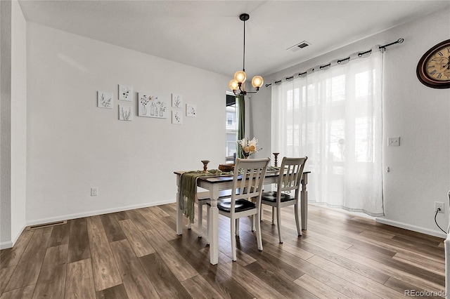 dining room with baseboards, a notable chandelier, wood finished floors, and visible vents
