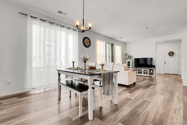 dining area with a chandelier, visible vents, and light wood-style floors
