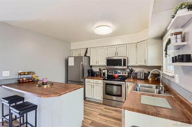 16602 E Gunnison Pl, Aurora, CO 80017 - kitchen with stainless steel appliances, wood counters, a sink, open shelves, and a kitchen breakfast bar