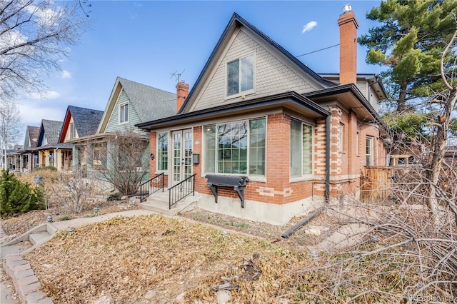 rear view of property with brick siding, a chimney, and entry steps