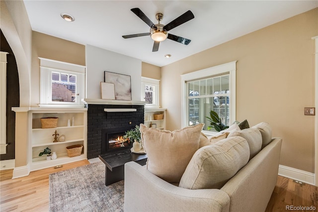 living area with wood finished floors, a fireplace, and a healthy amount of sunlight