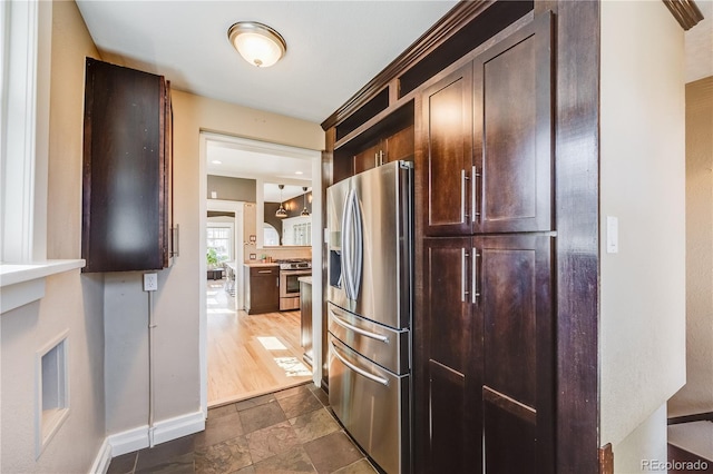 kitchen with baseboards, open shelves, stainless steel appliances, dark brown cabinets, and stone finish flooring