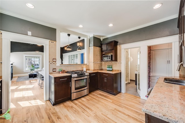 kitchen featuring a sink, stainless steel appliances, dark brown cabinets, and ornamental molding