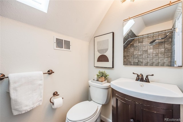 bathroom featuring visible vents, toilet, vaulted ceiling with skylight, walk in shower, and vanity