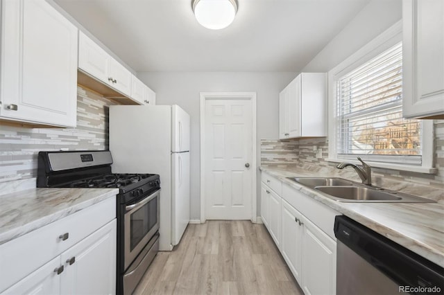 kitchen featuring stainless steel appliances, light countertops, white cabinets, a sink, and light wood-type flooring