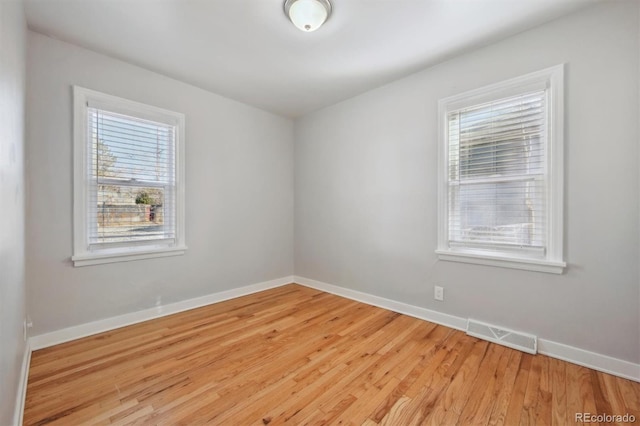 spare room featuring light wood-type flooring, baseboards, and visible vents