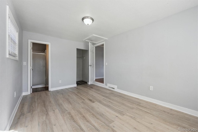 unfurnished bedroom with wood finished floors, visible vents, baseboards, a closet, and attic access