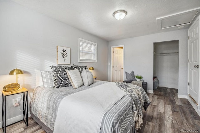 bedroom featuring a closet, wood finished floors, attic access, and baseboards